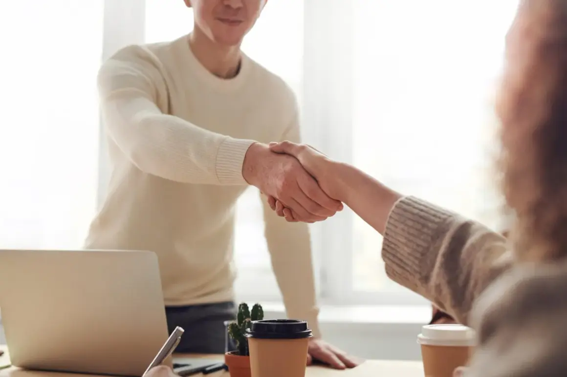 Händeschütteln im Büro: Ein Mann und eine Frau besiegeln eine neue berufliche Orientierung mit 40.