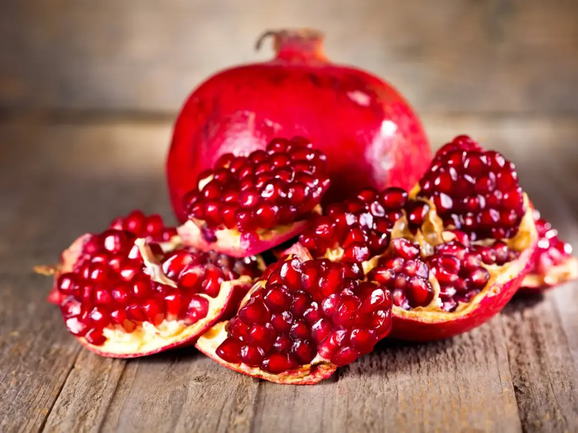 Saftige Granatapfelkerne auf Holz. Die Frucht, woher kommt der Granatapfel, stammt ursprünglich aus Persien und dem Nahen Osten.