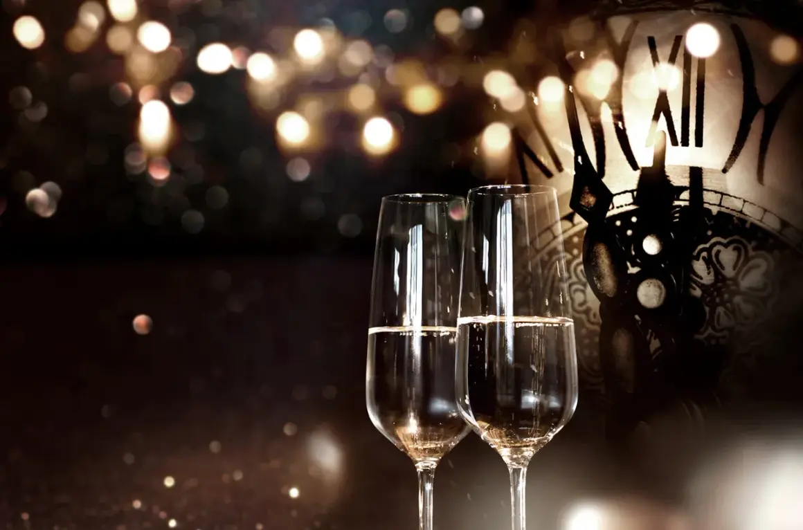 Zwei Sektgläser stehen vor einem antiken Zifferblatt. Seit wann gibt es Champagner? Seit Jahrhunderten ein Symbol für festliche Anlässe.
