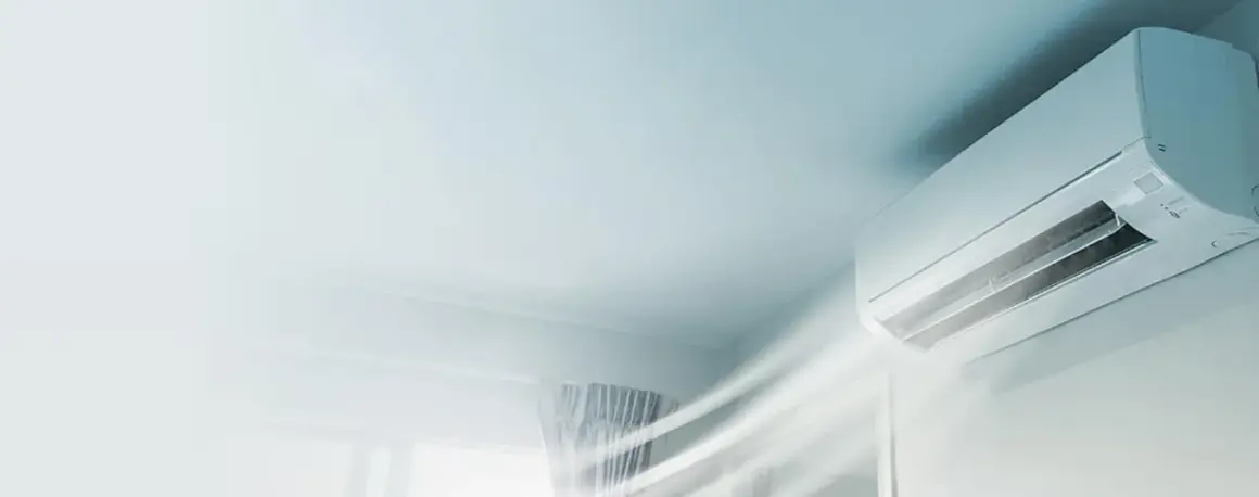 En vit luftkonditioneringsenhet på en vägg blåser ut sval luft. Snabb installation av AC för ett behagligt inomhusklimat.