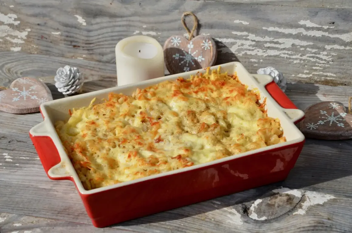 Un plat de gratin de crozet doré et gratiné, prêt à être dégusté. Une bougie et des décorations en bois en forme de cœur complètent la scène hivernale.