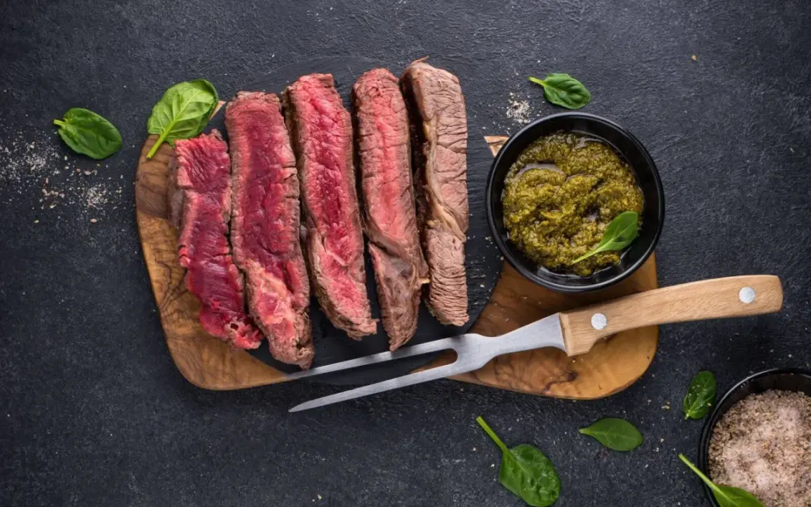 Perfekt gegrilltes Steak, in Scheiben geschnitten, mit Kräutersauce und frischem Spinat. Ein Genuss für jeden Fleischliebhaber.