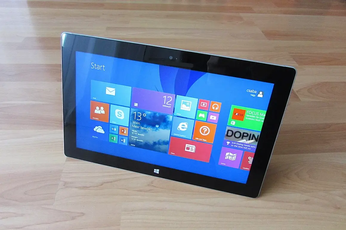 Tablet z interfejsem Windows 8, widok z góry, na drewnianym blacie.