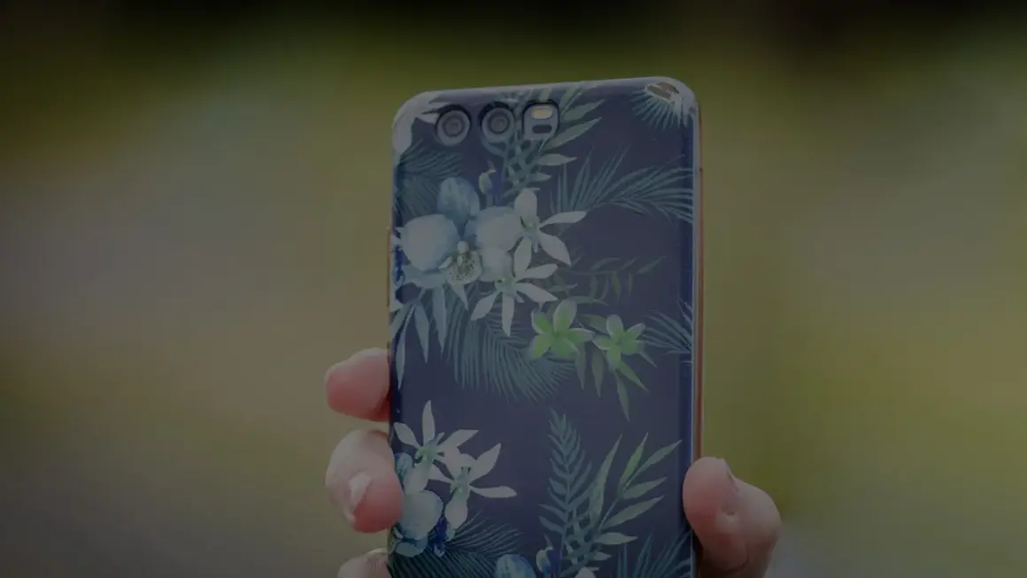 Dłoń trzyma telefon z motywem tropikalnych kwiatów. To jak przenośna galeria zdjęć w telefonie, pełna barw.