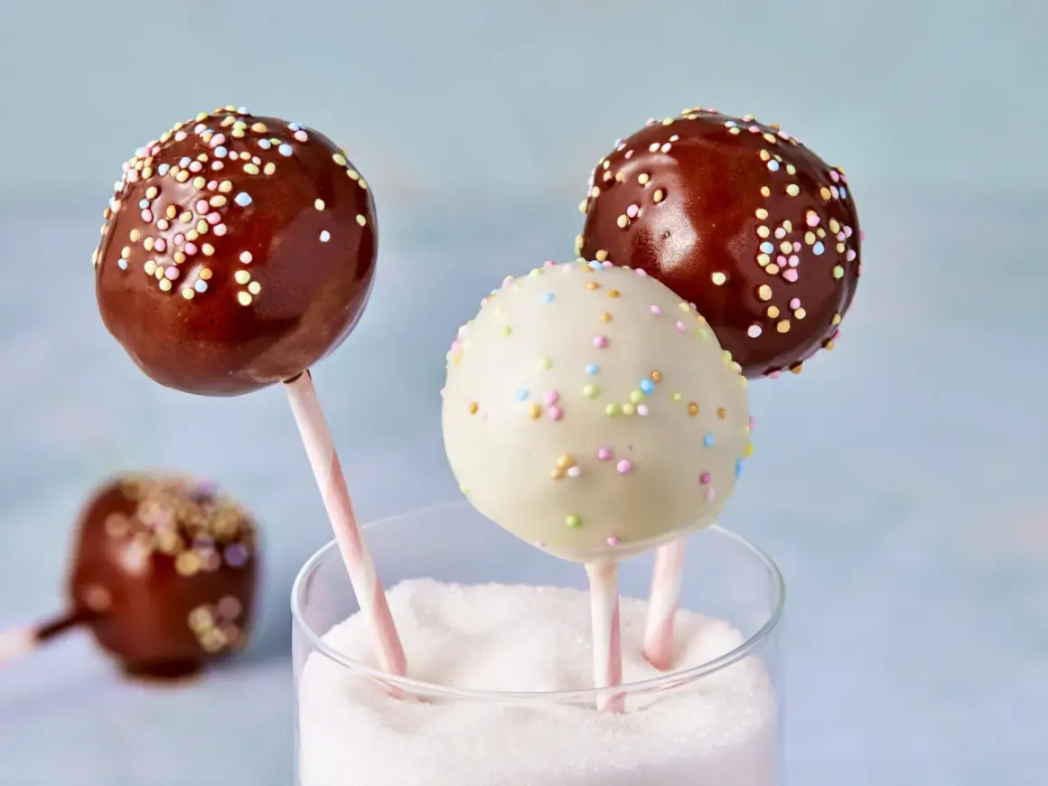 Leckere cake pops aus kuchenresten, verziert mit bunten Streuseln, stecken in einem Glas voller Zucker.