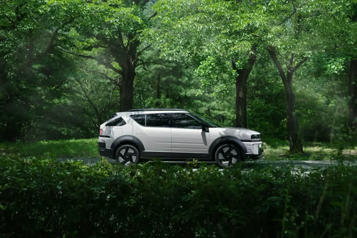Biały Tucson Hybrid na tle zielonego lasu. Niskie spalanie to jego atut podczas podróży po malowniczych trasach.