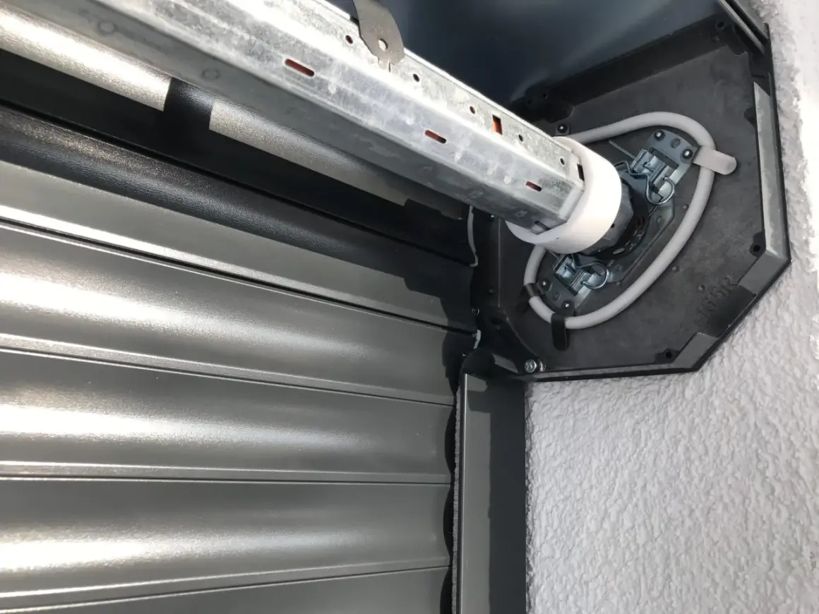 Naprawa żaluzji zewnętrznych: widok mechanizmu silnika i zwiniętego pancerza.