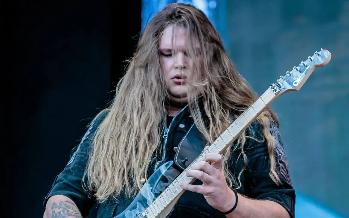 Tommy Johansson, con lunghi capelli biondi, suona la chitarra elettrica sul palco.