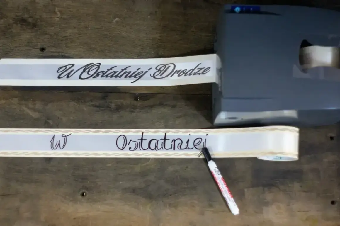 Taśma z napisem "W Ostatniej Drodze" przygotowywana do wieńca. Wzór jest elegancki i symboliczny.