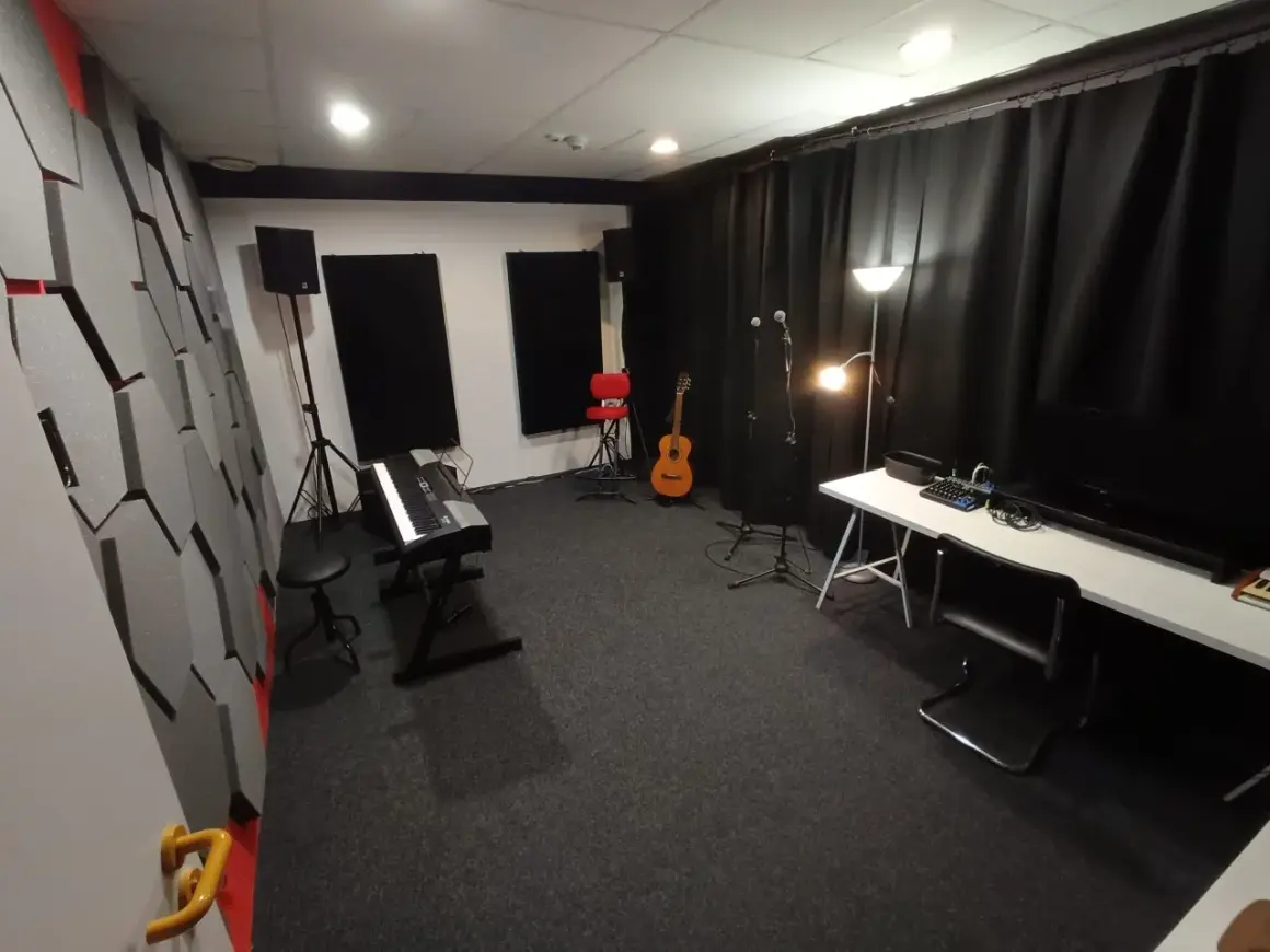 Studio nagraniowe z pianinem, gitarą i mikrofonami. Akustyka pomieszczenia, gdzie może pojawić się jitter, jest poprawiona przez specjalne panele na ścianach.