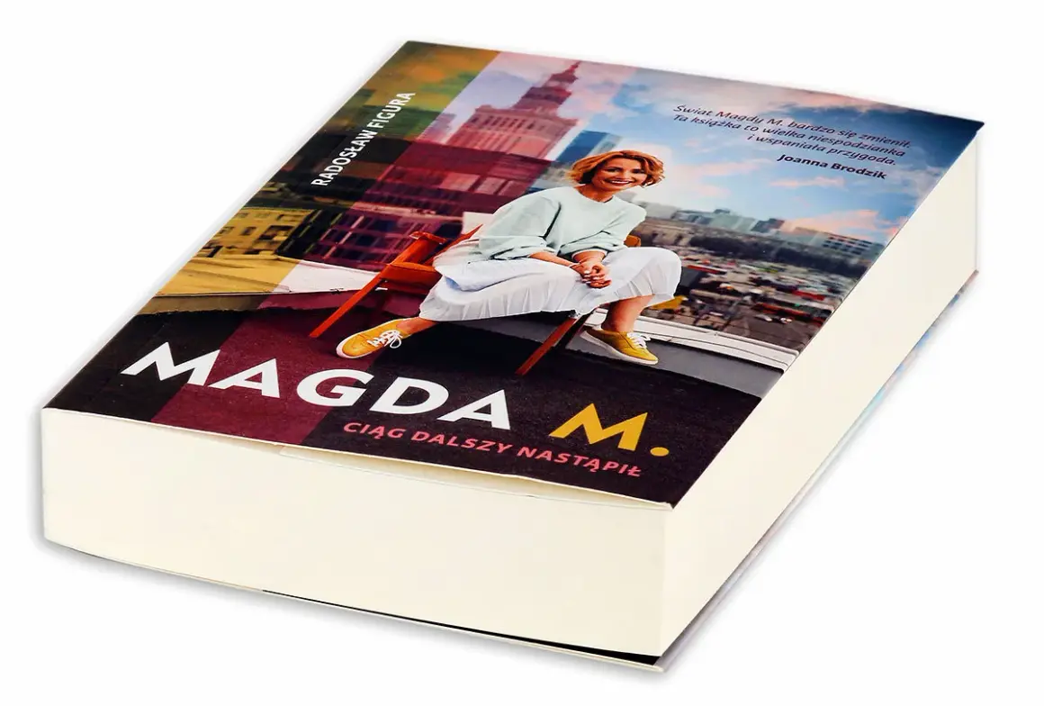 Okładka książki "Magda M. Ciąg dalszy nastąpił" z Radosławem Figurą. Uśmiechnięta Magda M. siedzi na krześle na tle panoramy miasta.