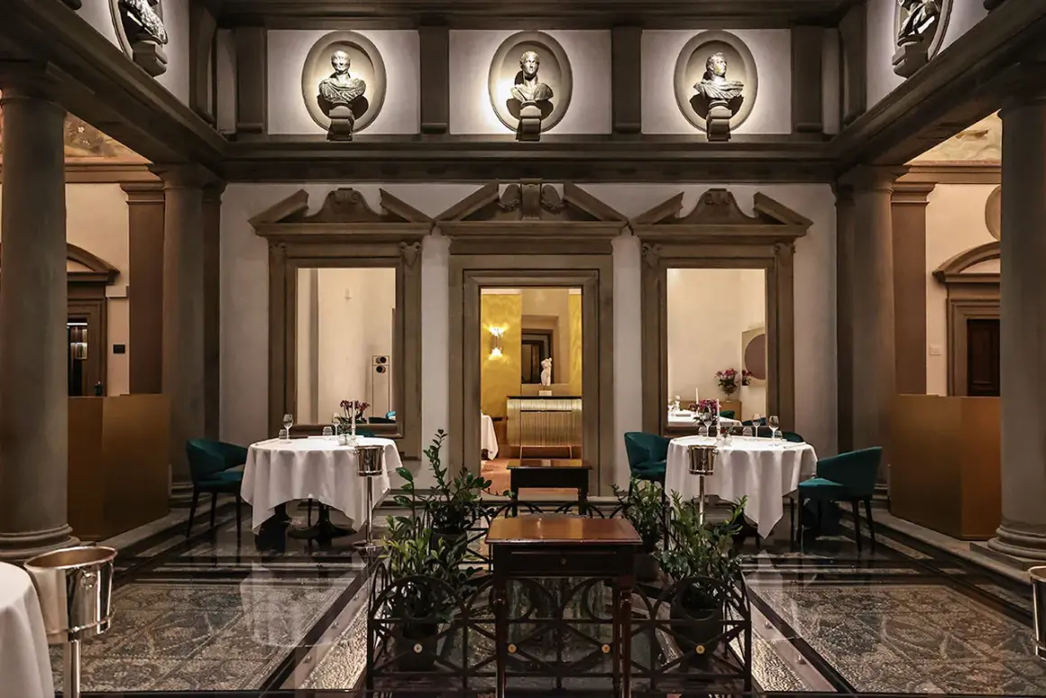 Lussuoso ristorante con tavoli apparecchiati, busti antichi e colonne. Un'atmosfera da vero atto di vito mollica.