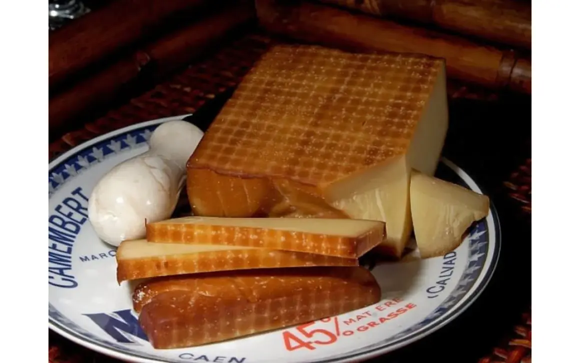 Wędzony ser na talerzu z napisem "Camembert". Obok kawałki sera i biały ser. Idealny do solanki do sera do wędzenia.