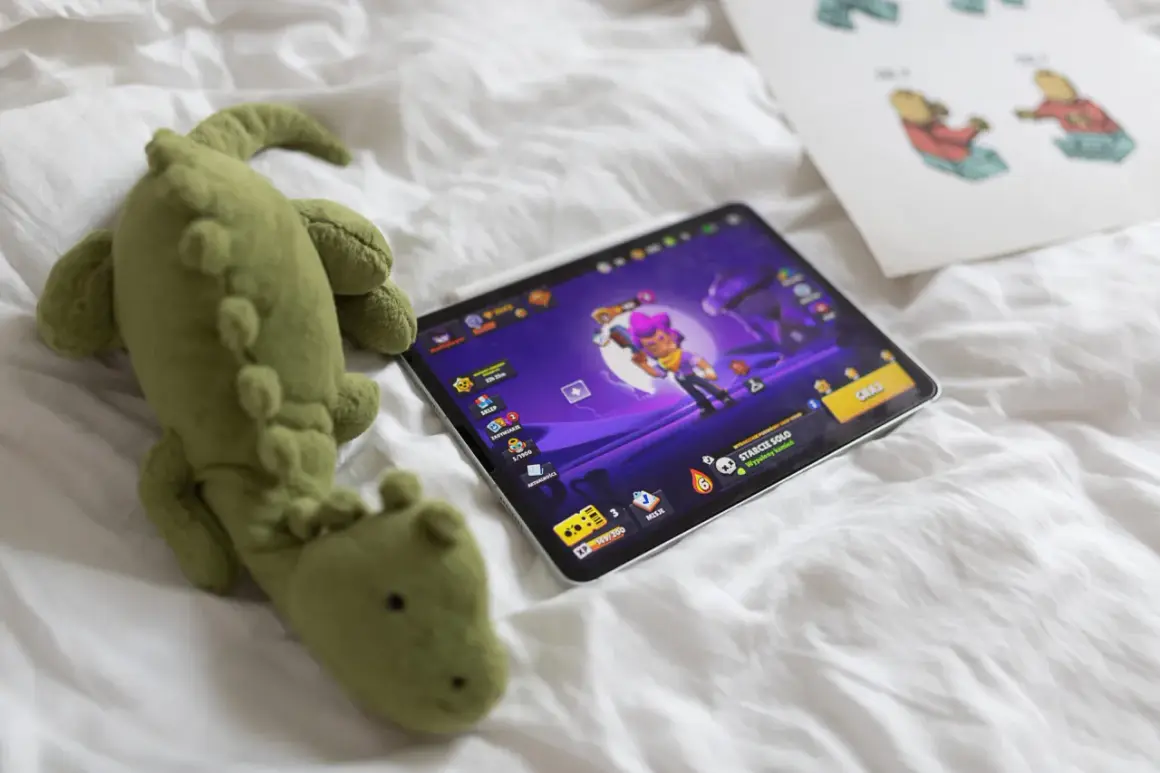 Pluszak-krokodyl obok tabletu z grą Brawl Stars. Zastanawiasz się, brawl stars od ilu lat jest dostępne?