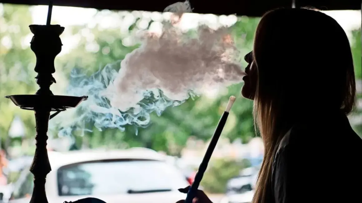 Silhouette einer Frau, die eine Shisha raucht. Dichter Rauch steigt auf und umhüllt ihr Gesicht. Ein **Rauchmelder** wäre hier fehl am Platz.