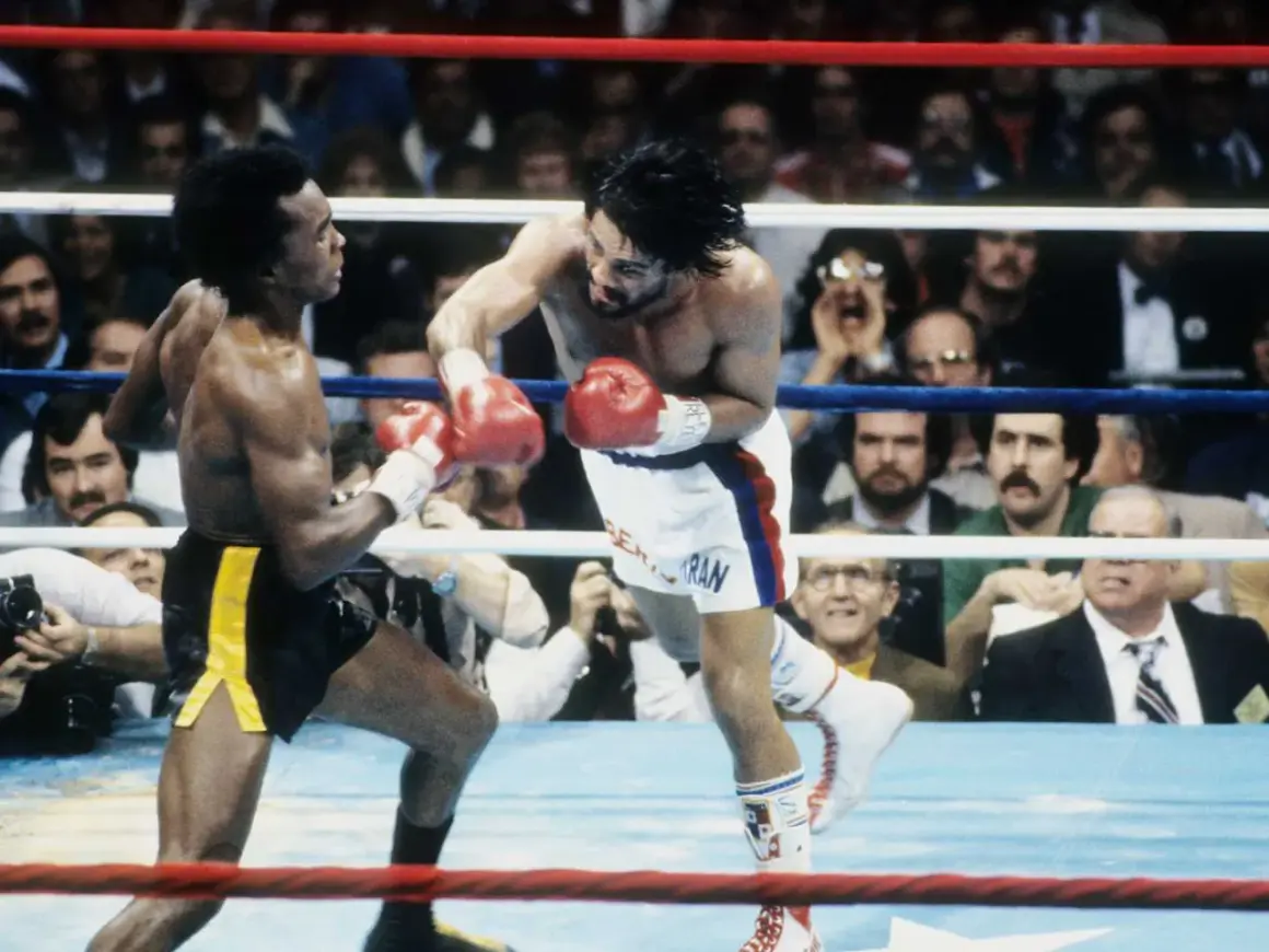 Sugar Ray Leonard lands a punch on Roberto Duran in a fierce boxing match. The crowd watches intently as the two legends battle in the ring.