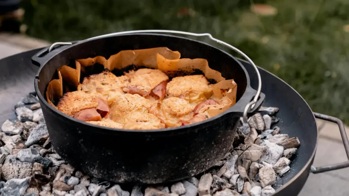 Ein Gusseisentopf mit einem leckeren Crumble, der über glühender Kohle für das **Winter grillen** zubereitet wird.