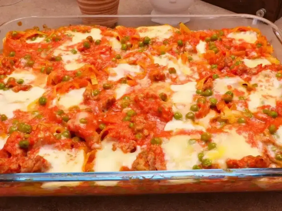 Nidi di tagliatelle al forno con ragù, piselli e mozzarella filante, un piatto invitante e saporito.