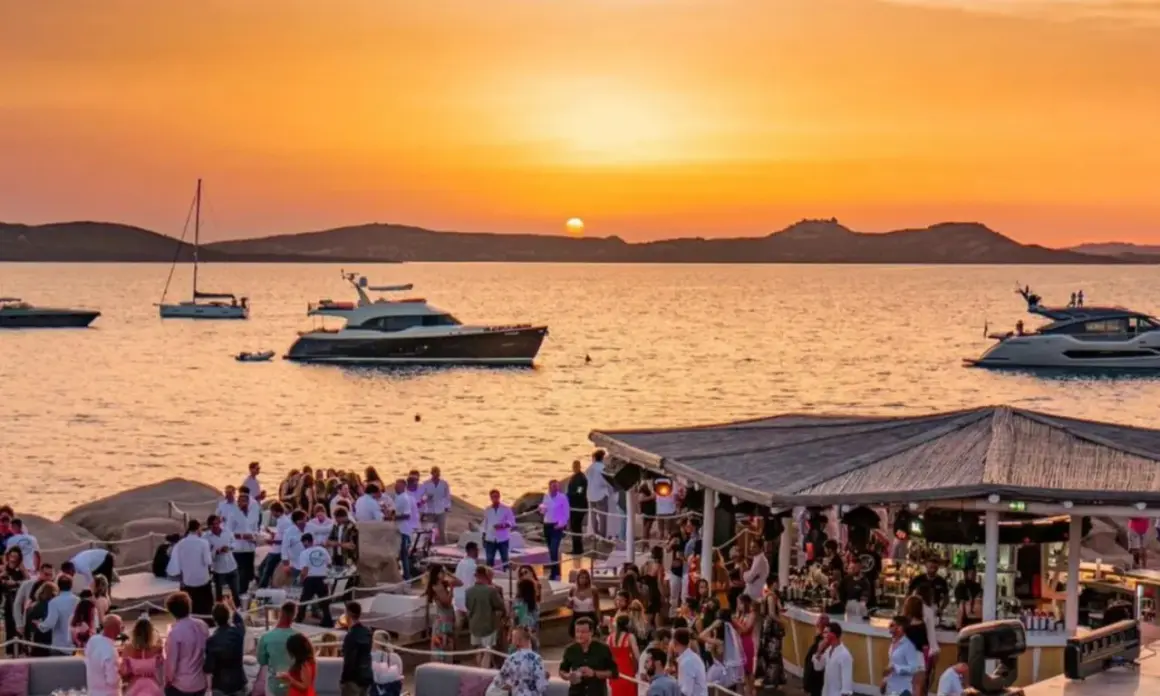 Tramonto dorato su un phi beach affollato, con yacht e bar sulla spiaggia.