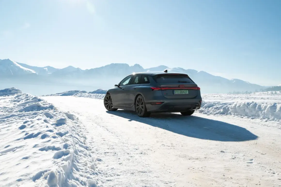 Audi A6 e-tron na śnieżnej drodze z górami w tle.