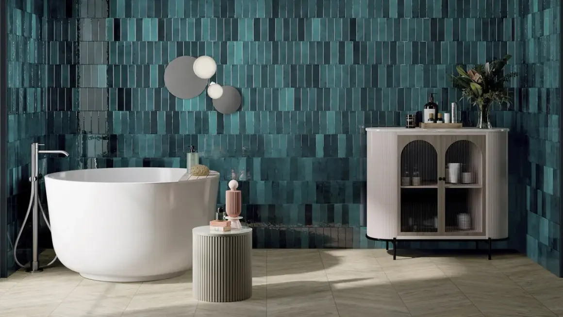 Une salle de bain moderne avec des carreaux muraux bleu sarcelle profonds, une baignoire îlot blanche et un meuble de rangement élégant. Une belle idée couleur salle de bain pour une ambiance chic.