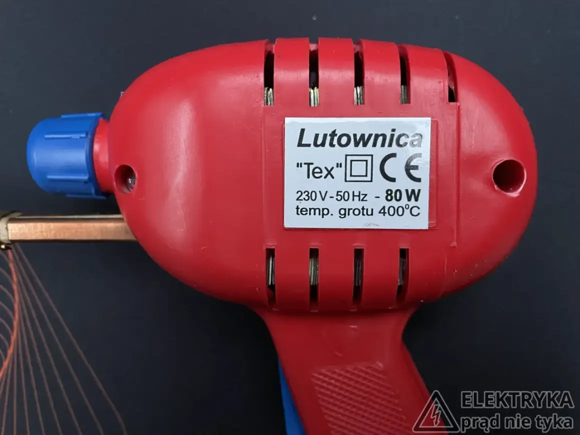 Czerwona lutownica "Tex" z niebieskim elementem, o mocy 80W i temperaturze grotu 400°C. Posiada oznaczenie CE, wskazujące na zgodność z normami bezpieczeństwa, w tym klasy ochronności.