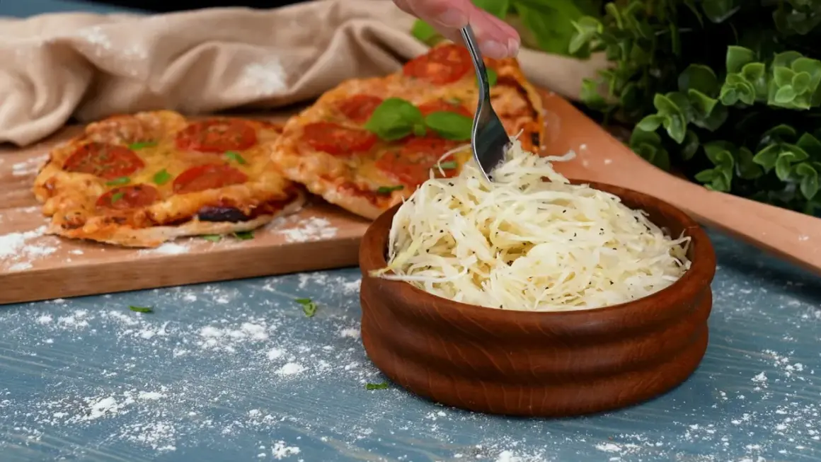 En skål med krispig pizzasallad bredvid en pizza med tomater. Perfekt tillbehör för ditt pizzasallad recept.