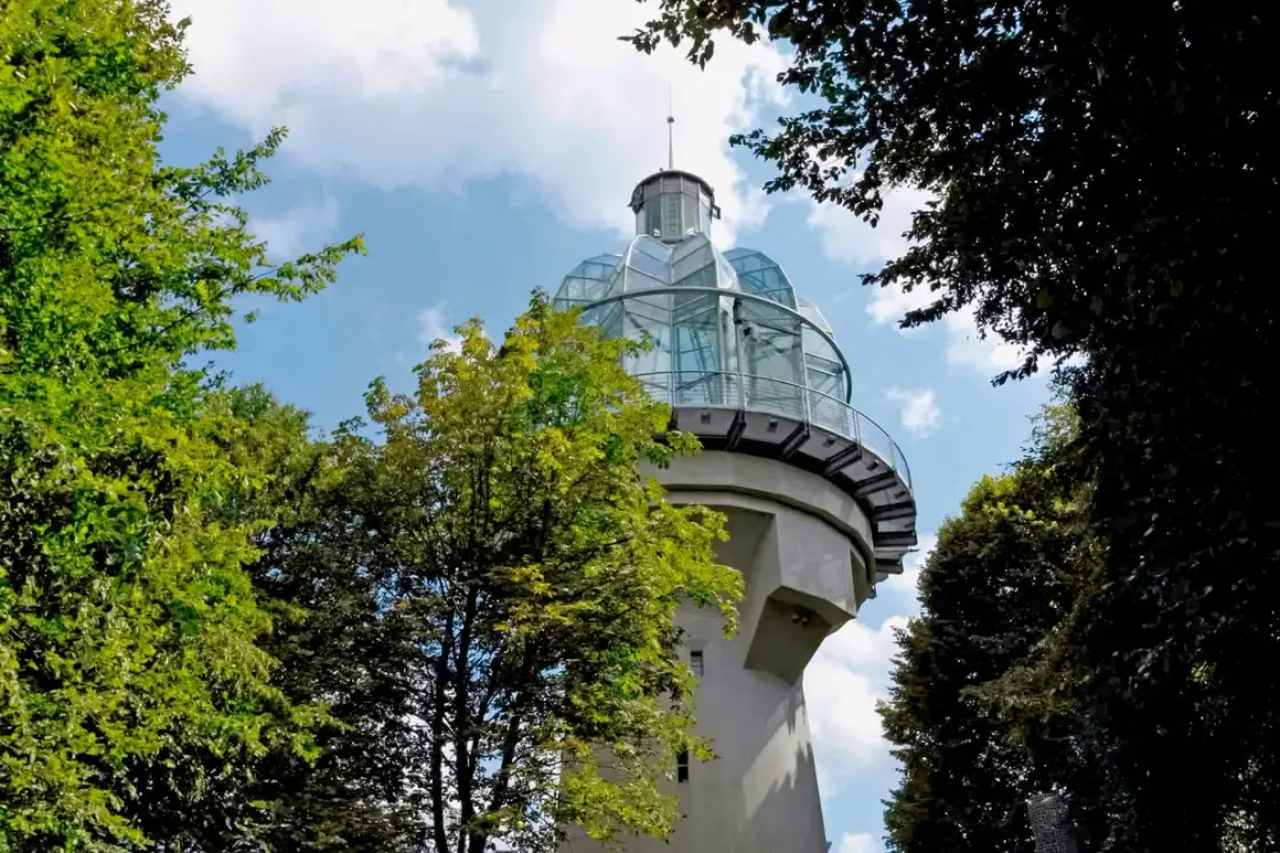 Ein Aussichtsturm mit Glaskuppel, ideal für bergische schweiz wandern. Umgeben von grünen Bäumen und blauem Himmel.