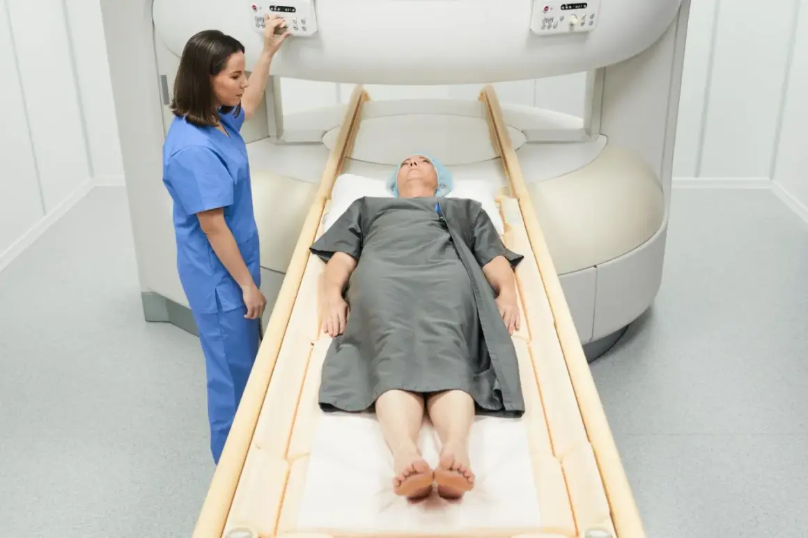 Pacjent leży na stole do rezonansu magnetycznego, pielęgniarka przygotowuje badanie. Rezonans biodra pomoże zdiagnozować problem.