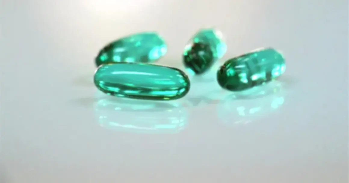 Zielone kapsułki leżą na białym tle. Czy ibuprofen jest szkodliwy? To pytanie nurtuje wiele osób.