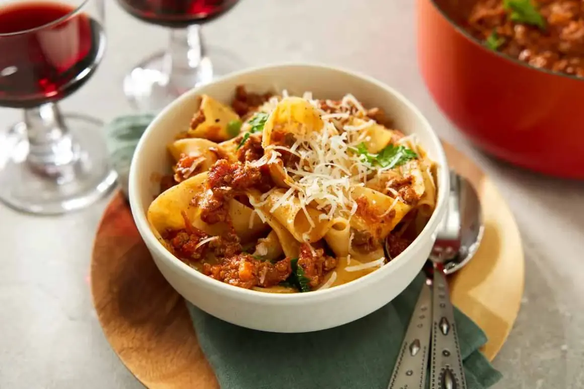 En skål med paccheri pasta med en mustig ragu, toppad med riven parmesan. Perfekt för ett mysigt middagsrecept.