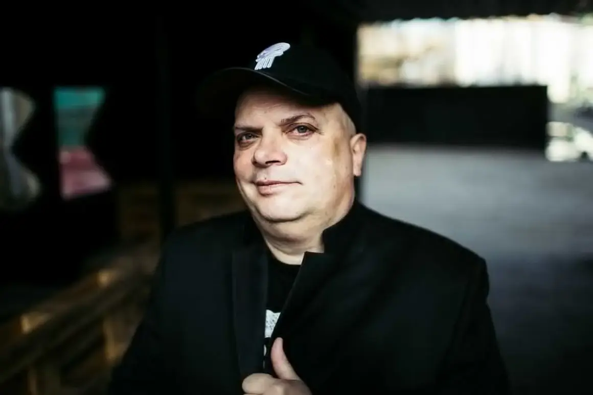 Krzysztof Skiba w czapce z daszkiem i czarnej marynarce, jakby przygotowywał się do wykonania swoich kultowych utworów.