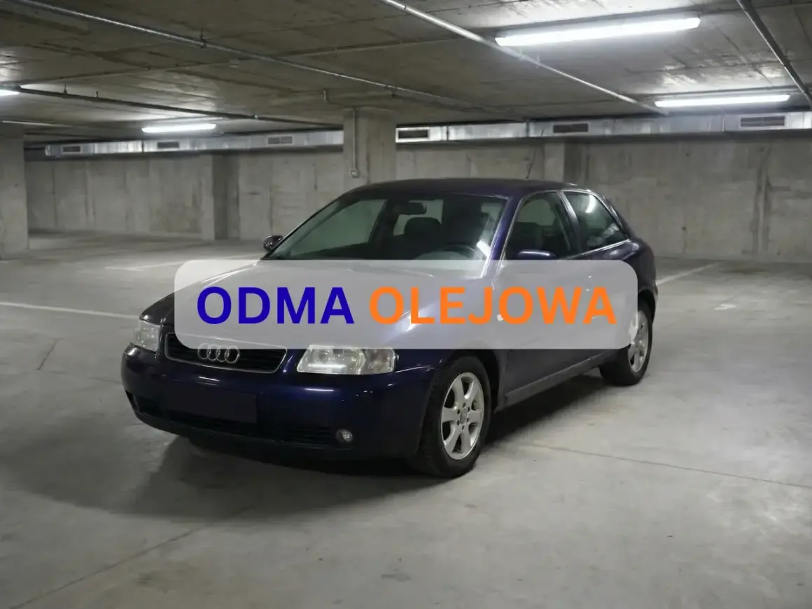 Granatowe Audi A4 w garażu. Napis "ODMA OLEJOWA" sugeruje uszkodzony separator oleju objawy.