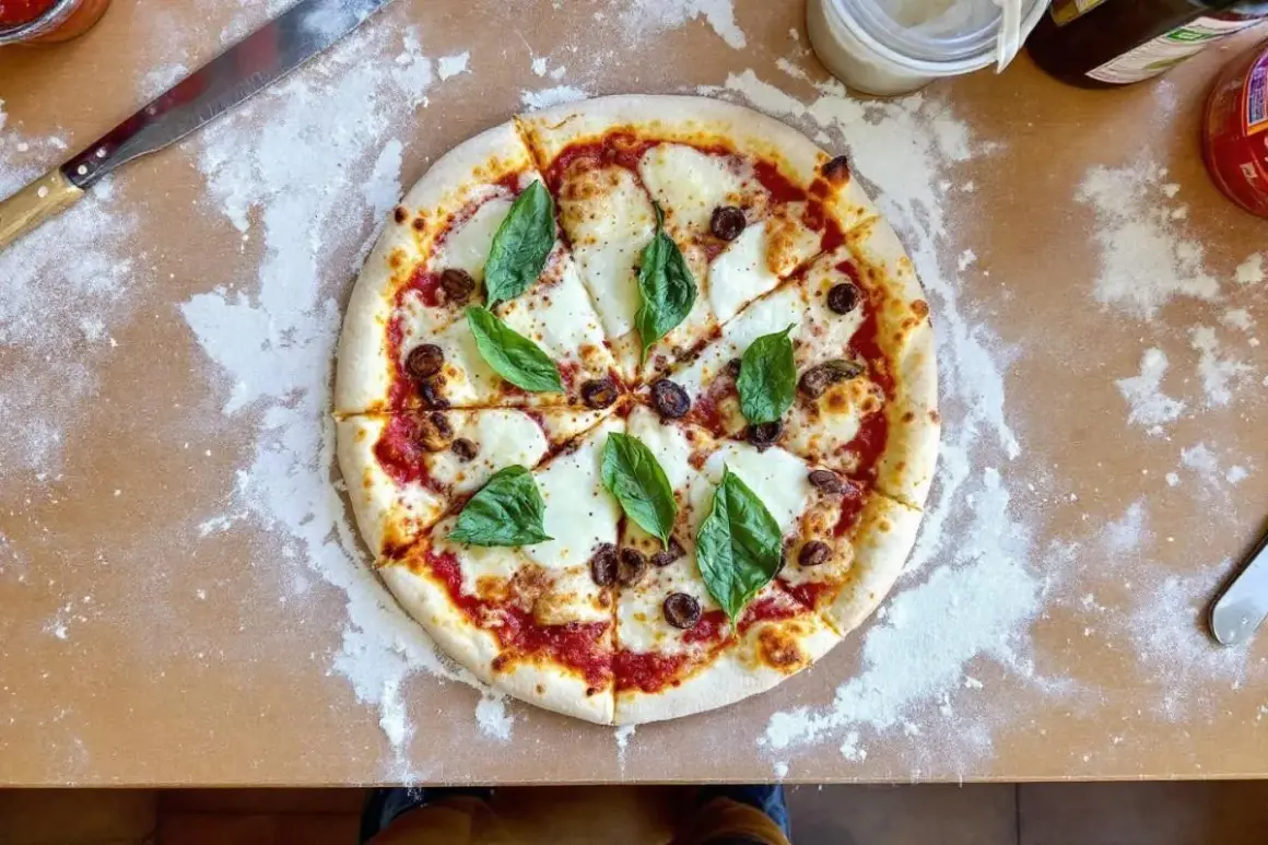 Pizza Margherita fraîchement sortie du four, avec son fromage fondant, ses olives et son basilic. Le temps de cuisson pizza four 250°C est parfait.