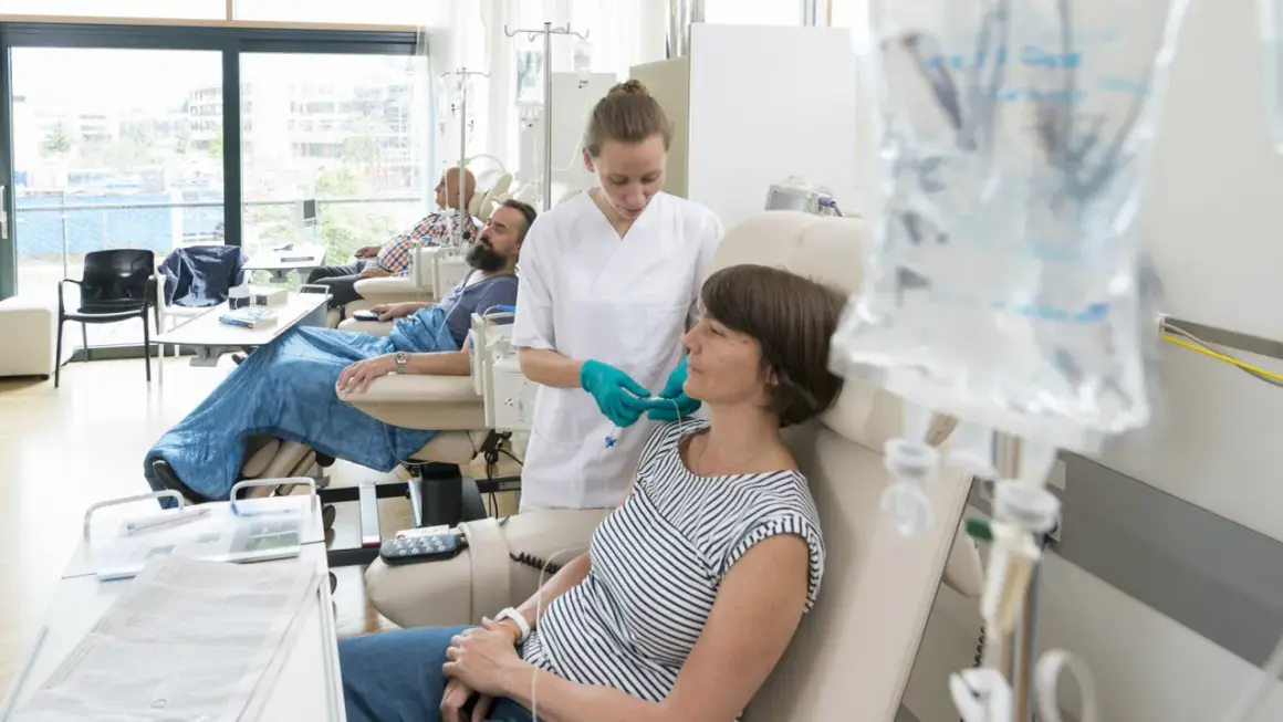 Eine Krankenschwester verbindet eine Patientin mit Infusion. Sie verträgt die chemo gut, ein gutes Zeichen.