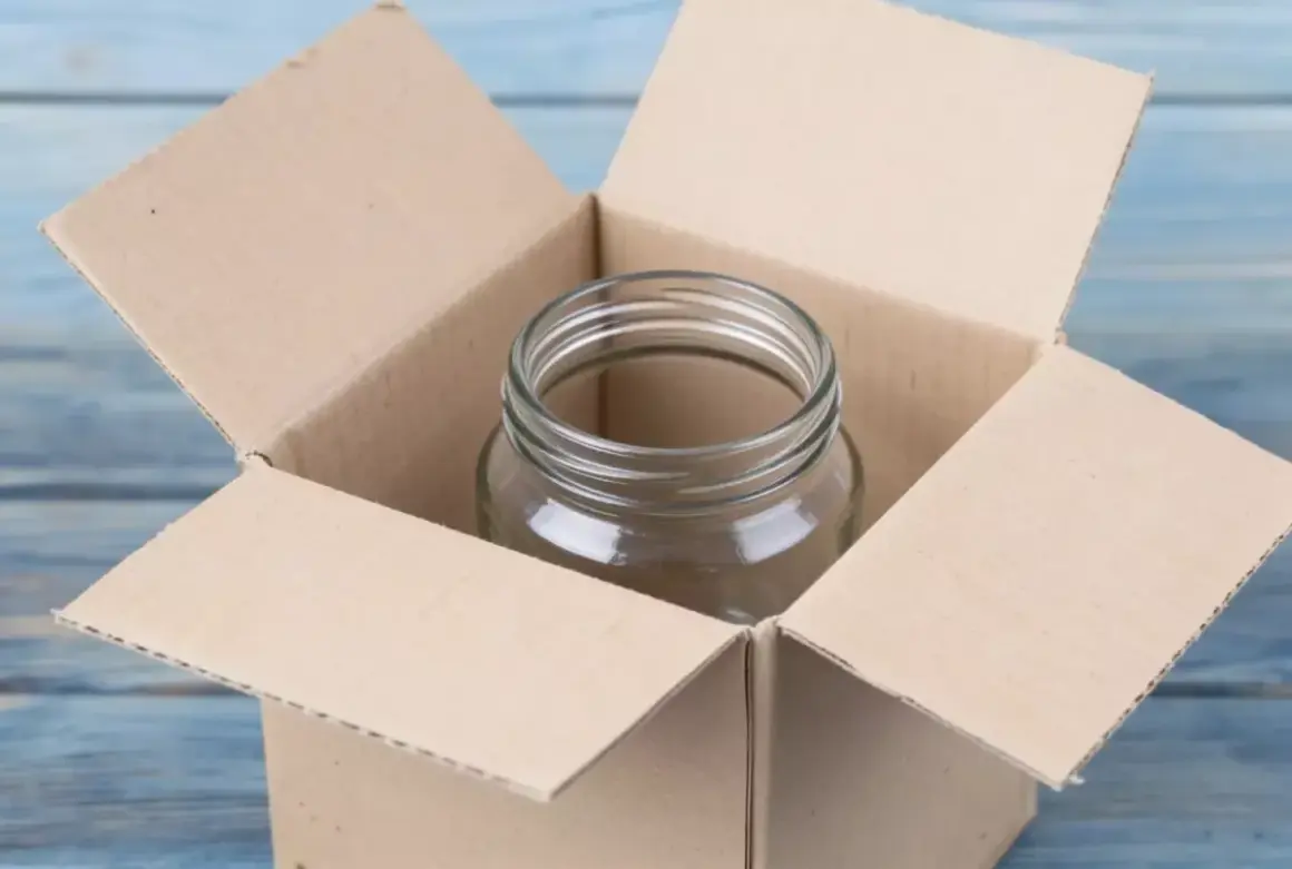 Puste szklane naczynie w otwartym kartonie. Ostrożnie szkło, aby się nie stłukło podczas transportu.