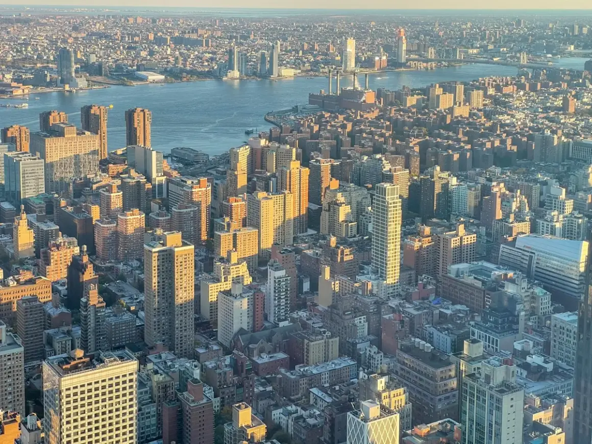 Widok z lotu ptaka na Manhattan i Brooklyn o zachodzie słońca. Rzeka Hudson rozdziela dwa miasta, a światła miasta zaczynają migotać.