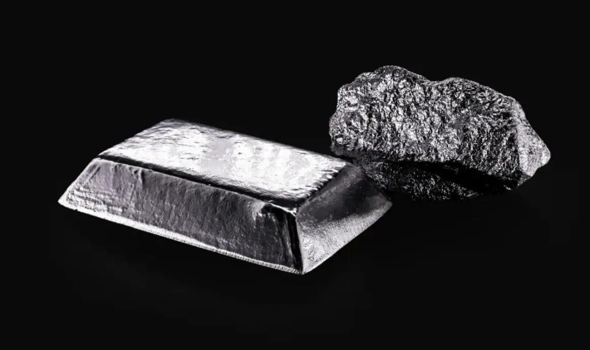 Sztabka i bryła platyny, najdroższego metalu na świecie, lśnią na czarnym tle.