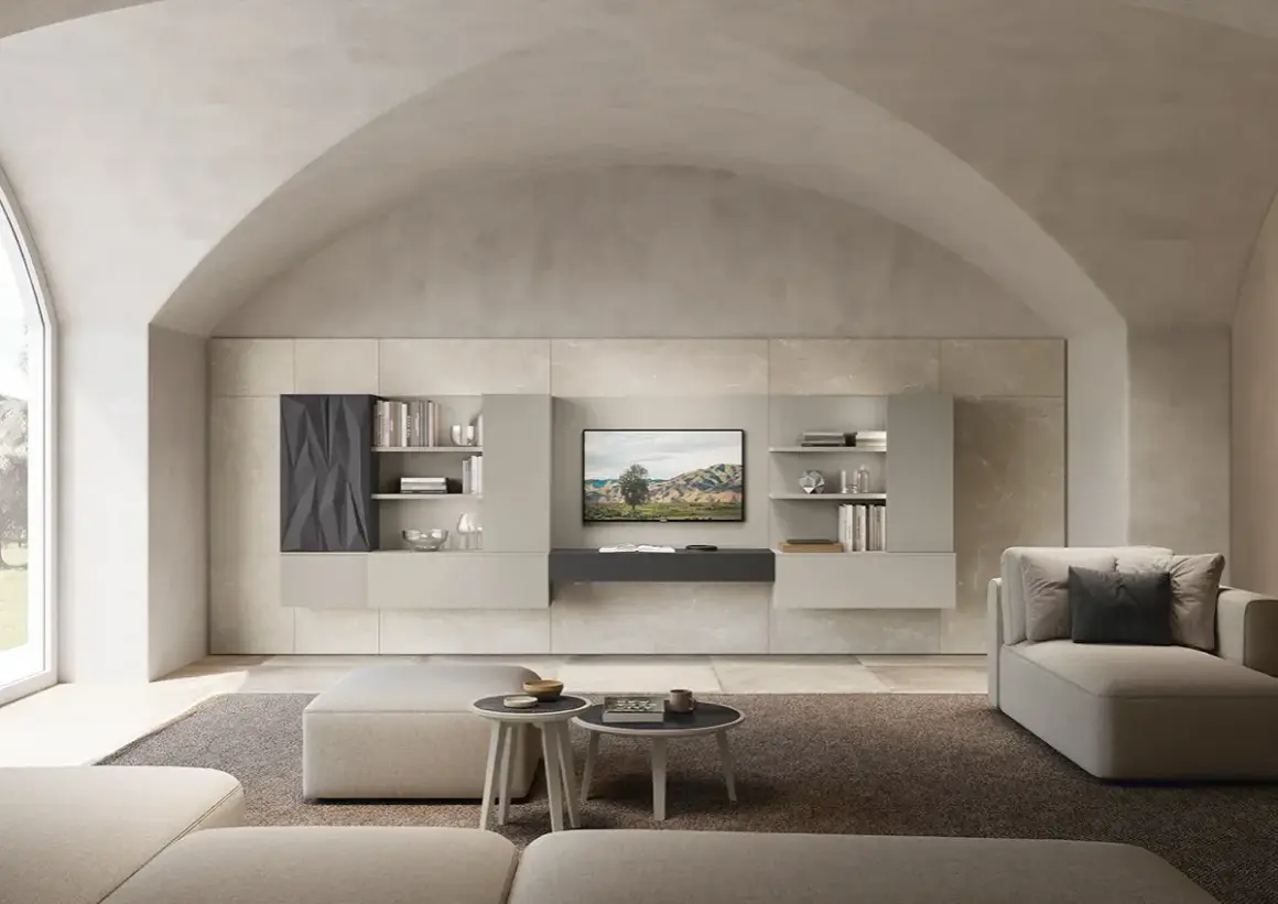 Soggiorno moderno con divano, pouf e parete attrezzata. La **casa color sabbia** è illuminata da un grande lucernario ad arco.