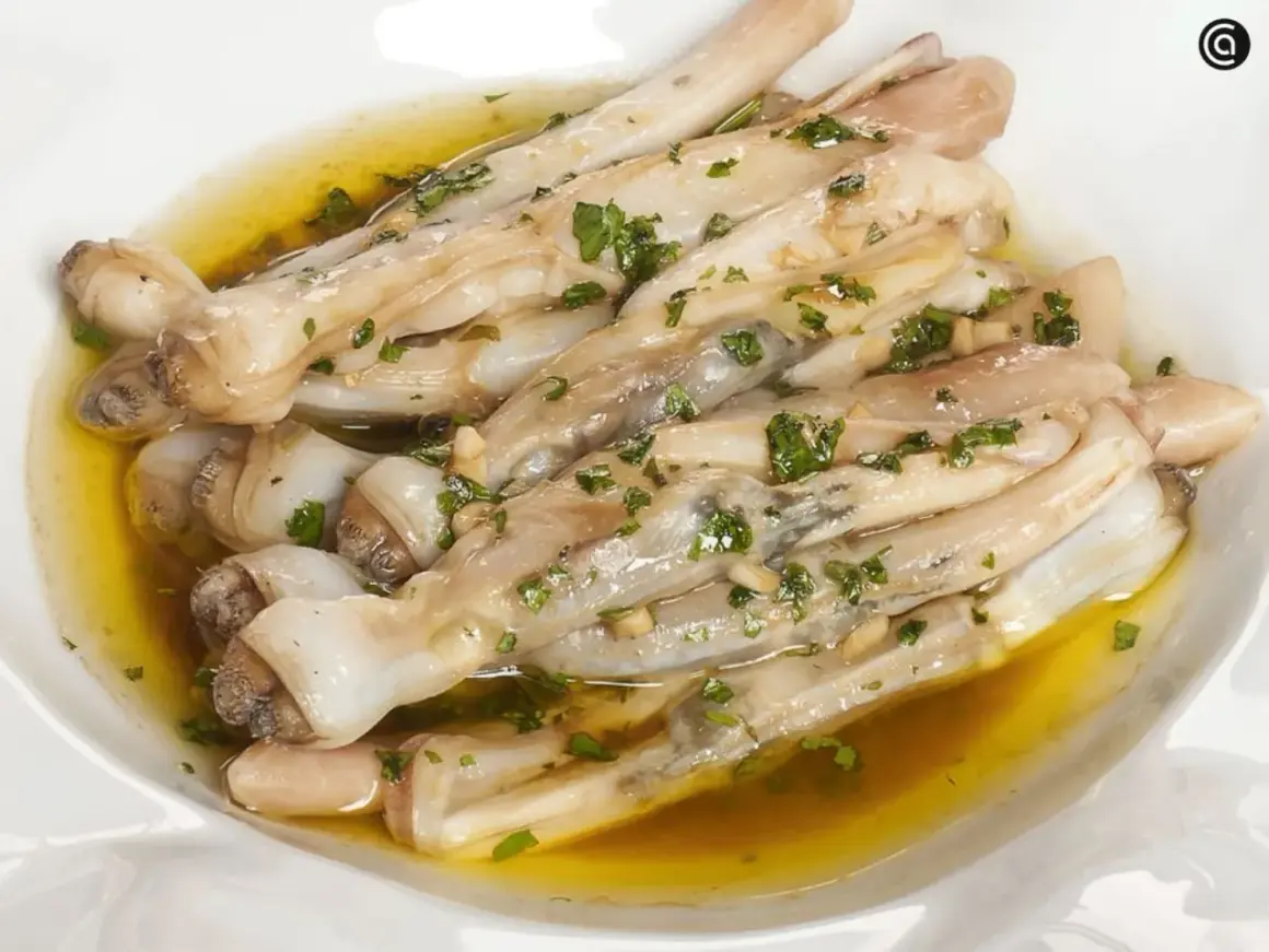 Navajas a la plancha con ajo y perejil, servidas en un plato blanco con aceite dorado.