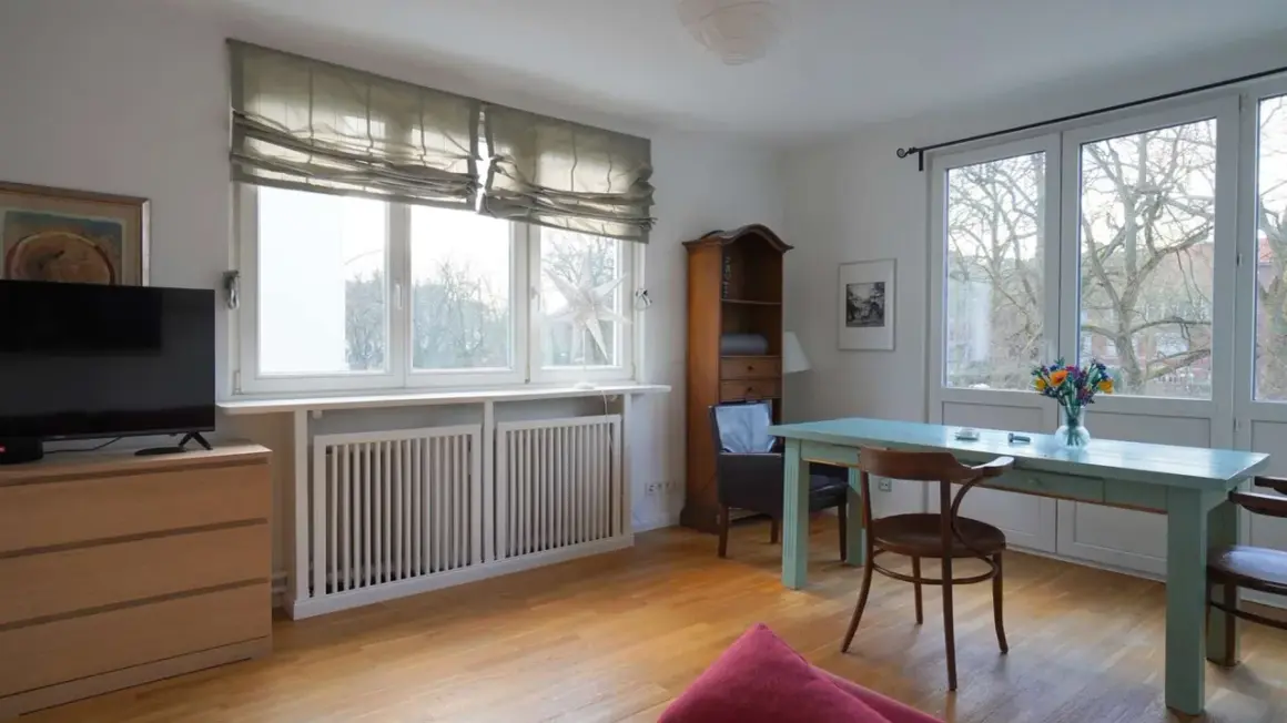 Gemütliche schlafnische im wohnzimmer mit TV, Bücherregal und Esstisch. Große Fenster lassen viel Licht herein.