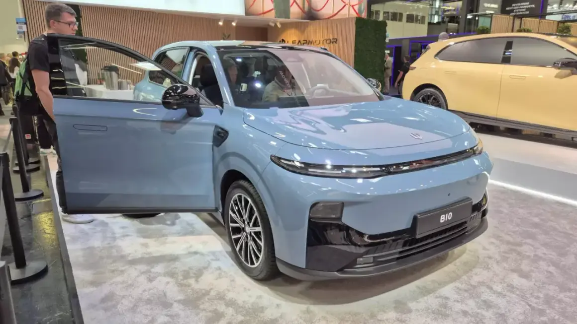 Niebieski SUV z otwartymi drzwiami, prezentujący nowoczesny typ nadwozia. Obok stoi żółty samochód.