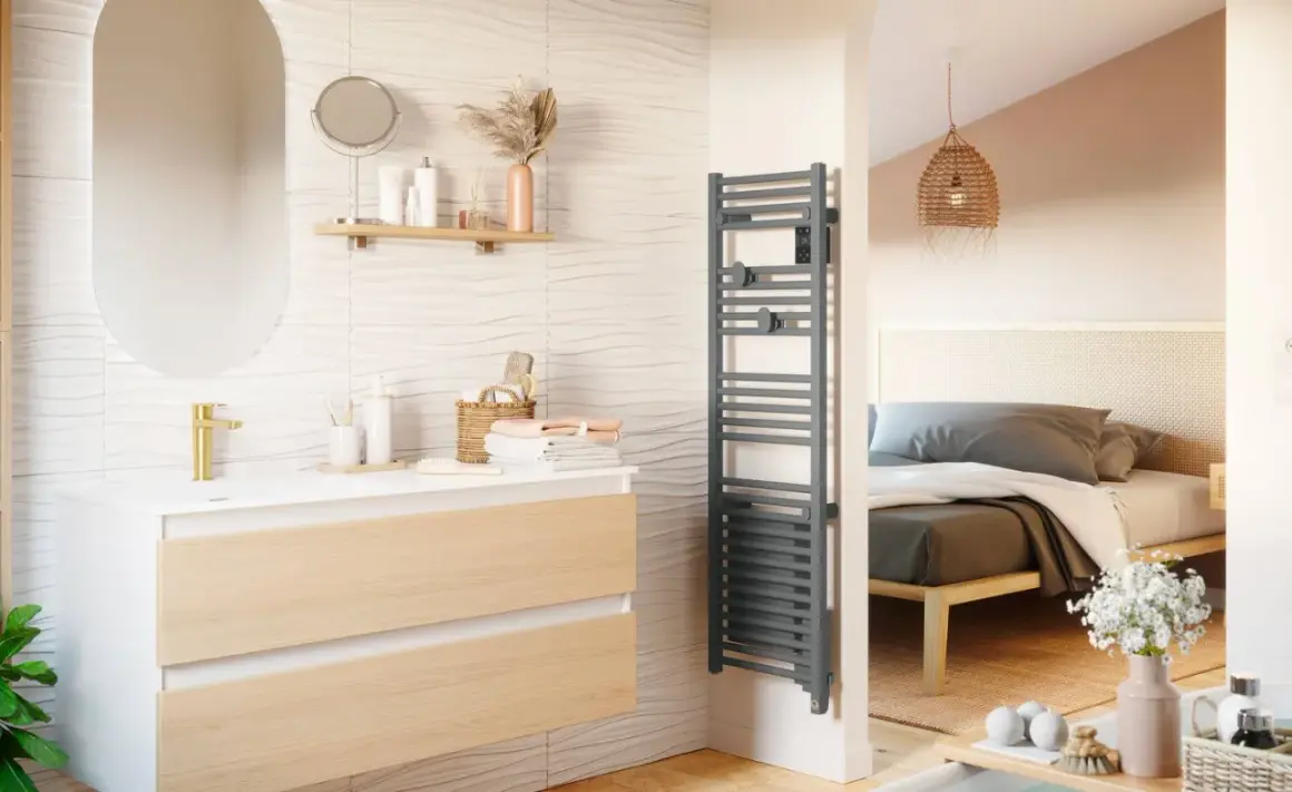Salle de bain moderne avec meuble vasque, miroir ovale et sèche serviette gris. La puissance du sèche serviette assure des serviettes chaudes.