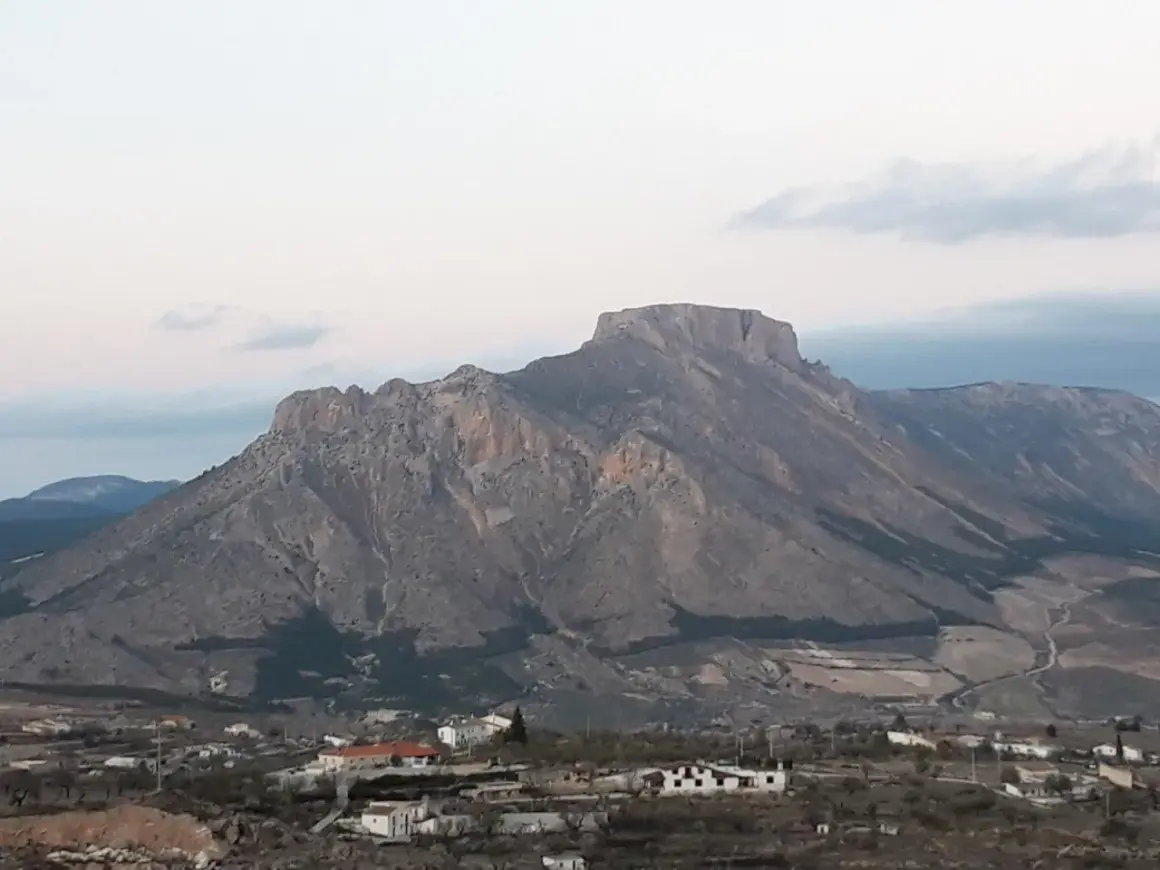 Majestuosa sierra de la Muela con sus picos rocosos y un pequeño pueblo a sus pies.