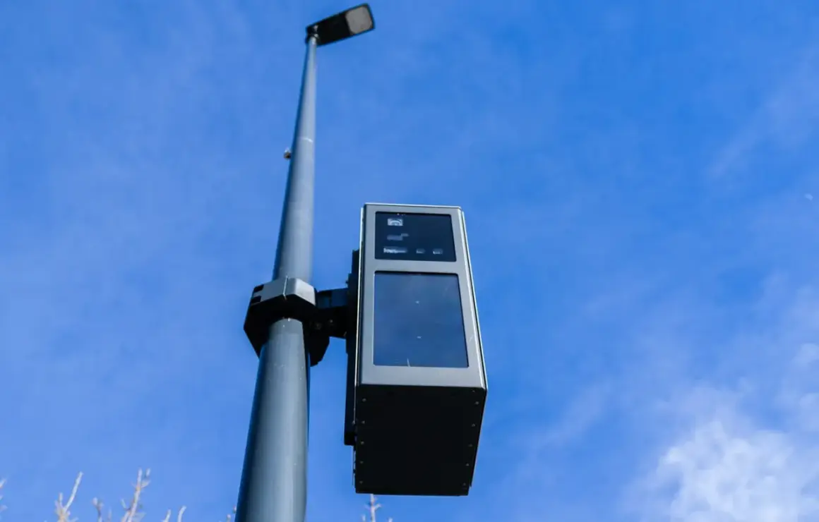 Un radar de ceinture, fixé sur un poteau, surveille la route sous un ciel bleu.