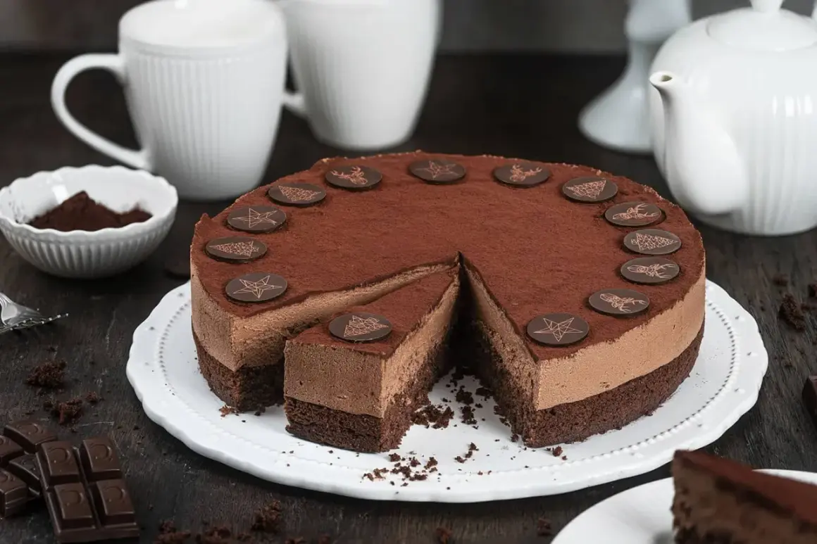 Eine köstliche Schoko Torte, bestäubt mit Kakao und verziert mit Schokoladensternen und Rentieren. Ein Stück ist bereits angeschnitten.