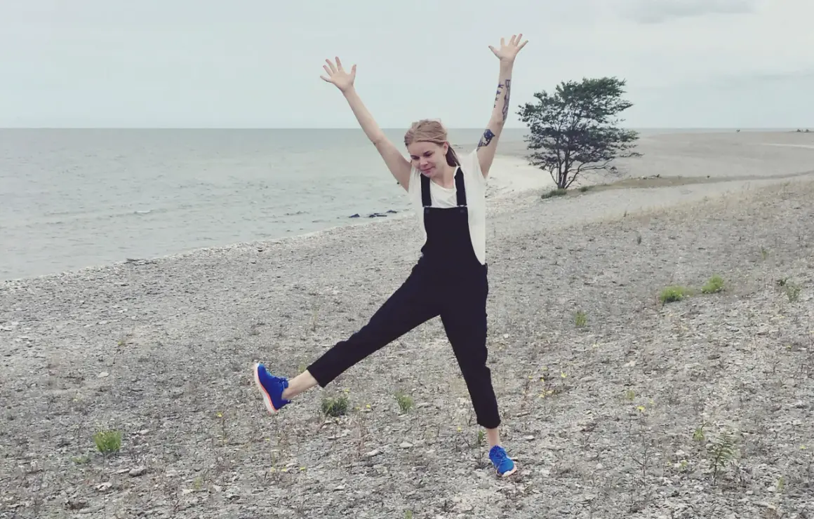 Glad tjej med armarna uppe på en stenig strand på Gotland i Sverige.