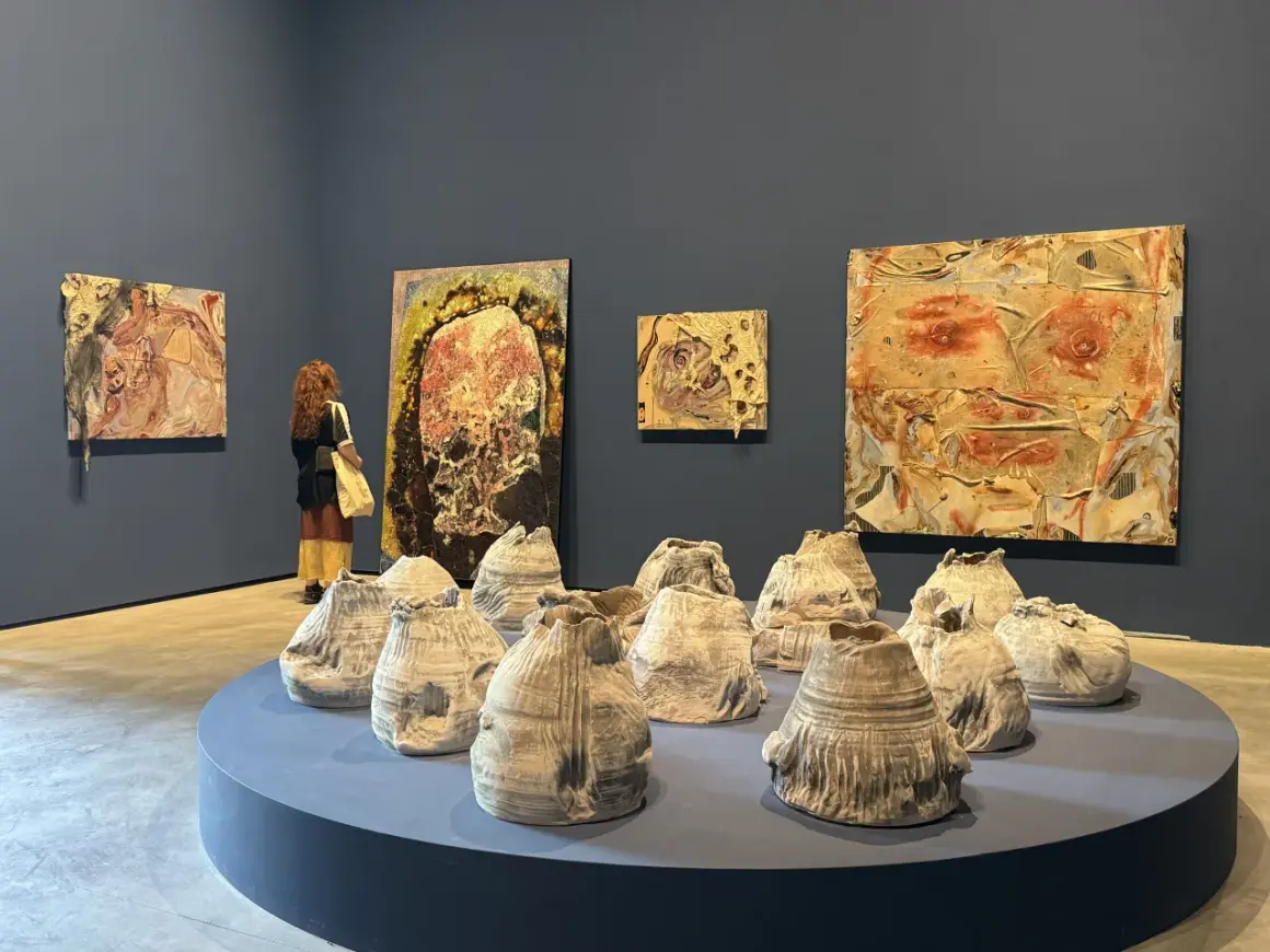 A visitor contemplates abstract artworks and ceramic sculptures at the Venice Biennale 2026.
