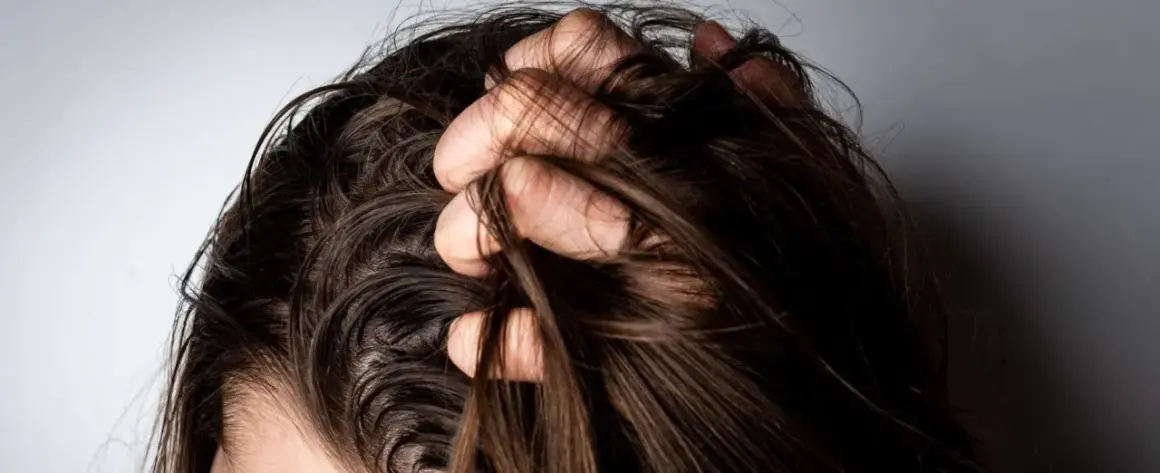 Mano revolviendo cabello oscuro. ¿Es mejor teñirse con el pelo sucio o limpio?