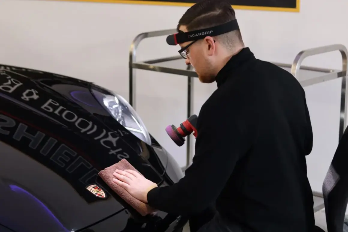 Man polerar en svart Porsche efter lackering med en polermaskin och mikrofiberduk.